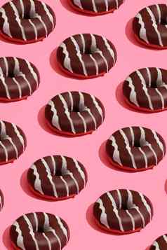 食物设计美味的巧克力上釉甜甜圈白色条珊瑚粉红色的柔和的背景前视图模式