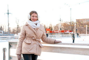 美丽的可爱的年轻的成人女人褐色头发温暖的冬天夹克站冰滑冰溜冰场背景小镇广场圣诞节情绪生活方式