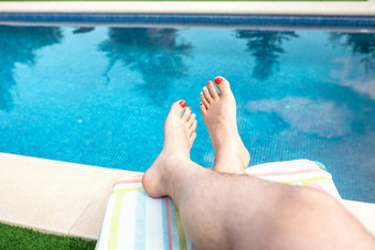 特写镜头只脚男人。放松太阳懒人游泳池光着脚男人。指甲画格特比克颜色概念旅行休闲