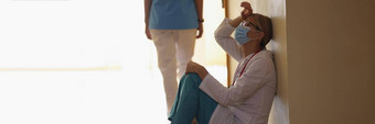 女外科医生呼气长操作坐着诊所走廊地板上
