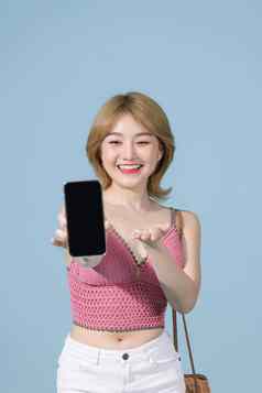 迷人的可爱的年轻的美丽的亚洲女人穿粉红色的前持有现代设备显示黑色的屏幕智能手机