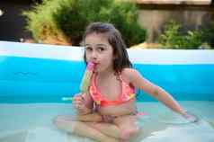 美丽的孩子女孩吃冰奶油户外充气游泳水池热阳光明媚的夏天一天