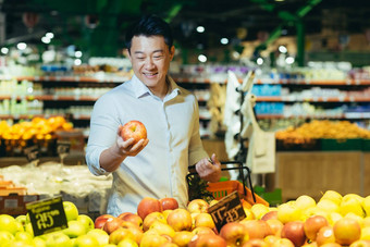 年轻的亚洲男人。选择选择生态袋苹果水果蔬菜超市