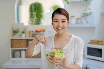 年轻的亚洲女人吃沙拉蔬菜饮食概念