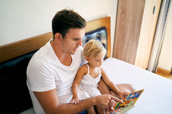 爸爸读取书色彩斑斓的图片女孩床上