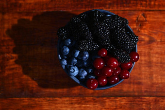 蓝色的陶瓷碗新鲜的成熟的<strong>即食</strong>有机蓝莓黑莓樱桃木背景