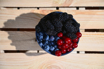 平躺新鲜的成熟的有机<strong>野生浆果</strong>蓝莓黑莓樱桃陶瓷碗木箱