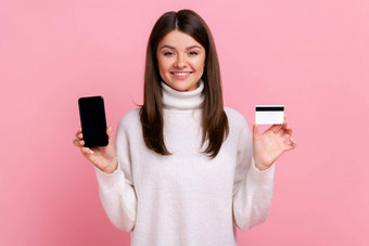 微笑乐观女持有信贷卡聪明的电话空显示广告