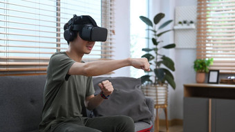 退出男人。玩视频游戏看电影虚拟现实耳机坐着沙发上舒适的首页
