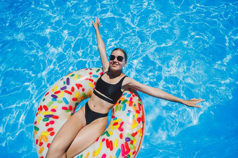 美丽的女人太阳镜池浮点数充气游泳环黑色的泳衣夏天照片游泳摄影夏天女人照片