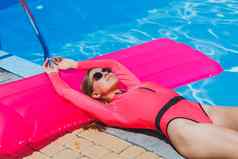 旅行池夏天假期奢侈品度假胜地女人放松粉红色的泳衣池粉红色的充气床垫绿松石背景池旅行概念