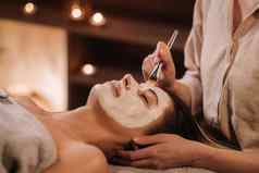 美容师使面具女人的脸恢复皮肤美容