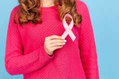 女人持有粉红色的丝带前面胸部乳房癌症