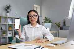 年轻的亚洲女人眼镜持有移动电话手显示电话电话模型