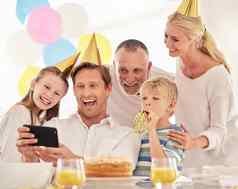 快乐家庭庆祝生日聚会，派对穿帽子采取自拍电话成熟的男人。采取照片父亲妻子孩子们聚会，派对使特殊的记忆