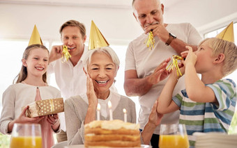 高级女人庆祝生日家庭首页穿聚会，派对帽子吹吹口哨奶奶生日蛋糕快乐的包围孙子儿子