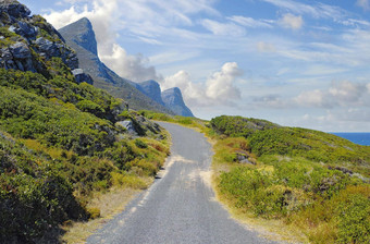 沥青路表格山多云的蓝色的天空景观农村巷道旅行山通过美丽的风景优美的自然开车郁郁葱葱的灌木角小镇南非洲