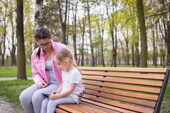 女孩<strong>运营</strong>智能手机坐着公园板凳上照顾者