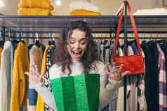 购物狂美丽的年轻的女孩女人服装商店购物中心喜乐购物者礼物站持有绿色纸袋背景衣架衣服包快乐