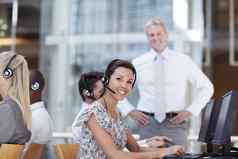 工作效率美丽的客户服务代表坐着电脑微笑同事经理背景