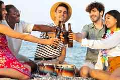 干杯微笑朋友享受冷啤酒海滩多样化的快乐年轻的人敬酒啤酒在户外