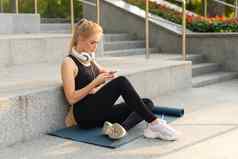 体育运动健身年轻的成人高加索人女人坐着锻炼席混凝土地板上休息早....锻炼户外夏天公园