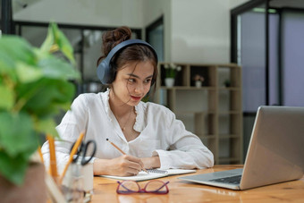 快乐年轻的亚洲女孩无线耳机移动PC屏幕阅读听在线课程研究远程首页由于流感大流行电晕病毒世界爆发检疫时间