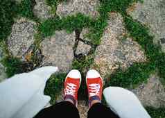 照片女腿红色的运动鞋白色鞋带石头绿色草