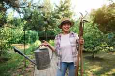 愉快的女园丁农民持有园艺工具手享受园艺有机蔬菜花园