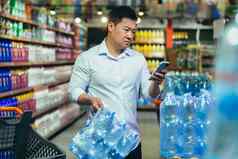 食物危机喝水短缺亚洲男人。超市购买瓶装水