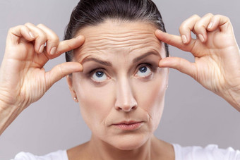 女人检查皱纹抗衰老的脸瑜伽练习公司收紧皮肤