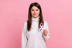 美丽的年轻的女人持有粉红色的丝带象征乳房癌症支持肿瘤学病人