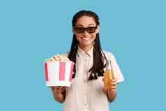 女人站眼镜持有爆米花饮料享受有趣的电影