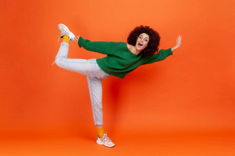 完整的长度肖像有趣的女人非洲式发型发型绿色休闲风格毛衣站腿假装飞行大喊大叫兴奋