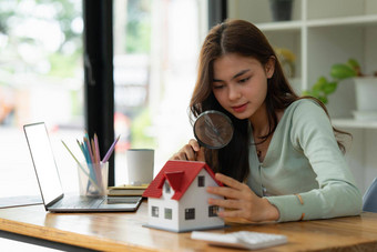 女人持有放大玻璃检查房子模型真正的房地产房子评估检查概念