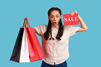 震惊了女人持有购物袋显示出售卡广告低价格购物中心