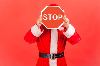 未知的男人。穿圣诞老人老人服装覆盖脸停止象征匿名人持有红色的交通标志警告禁止概念