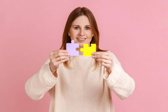 有吸引力的金发碧眼的女人持有黄色的紫色的谜题块解决任务相机