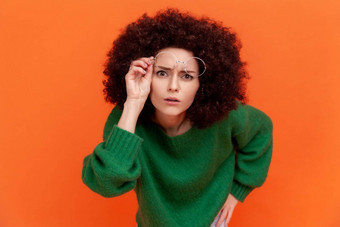好奇的女人非洲式发型发型穿绿色休闲风格毛衣提高光学眼镜盯着用心