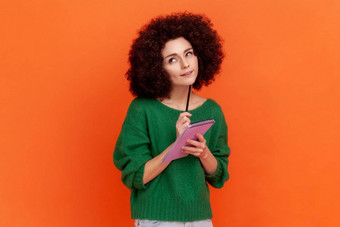 好深思熟虑的女人非洲式发型发型穿绿色休闲风格毛衣站纸笔记本笔使列表规划