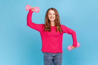 女人持有粉红色的哑铃手相机泵肌肉健康的生活方式