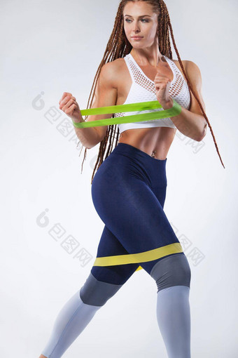 肌肉发达的年轻的适合体育女人运动员锻炼乐队扩张器健身房复制空间健身营养广告