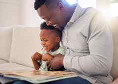 年轻的快乐非洲美国父亲阅读书儿子坐着沙发上首页男孩享受故事学习坐着沙发爸爸