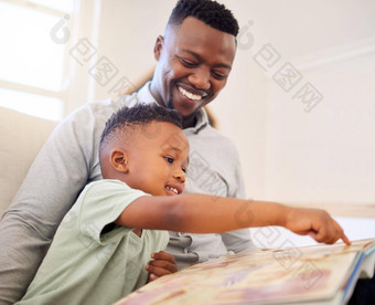 年轻的快乐快乐的非洲美<strong>国父</strong>亲阅读书儿子坐着沙发上首页男孩享受故事学习坐着沙发爸爸