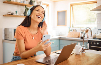年轻的快乐的混合比赛女商人持有电话穿耳机听音乐工作首页快乐的拉美裔女人社会媒体手机享受音乐打破工作移动PC