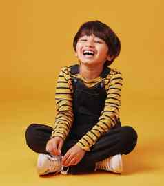 可爱的亚洲男孩坐着地板上休闲衣服笑穿越腿橙色Copyspace背景可爱的快乐男孩安全
