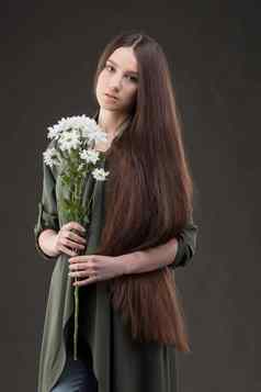 美丽的年轻的女孩自然美长光滑的头发持有花束白色菊花