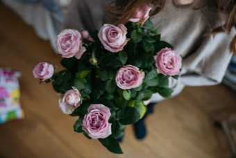 高视图年轻的女人持有花能粉红色的玫瑰布什