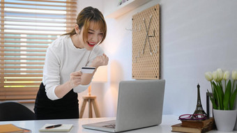 兴奋年轻的女人持有信贷卡移动PC屏幕在线购物互联网银行概念