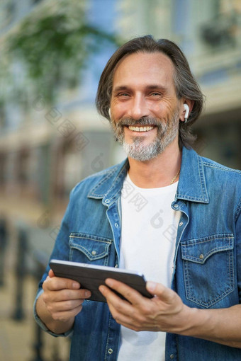 快乐微笑旅行英俊的成熟的男人。数字平板电脑会说话的在户外调用城市城市<strong>街道</strong>成熟的男人。听音乐无线耳机旅行小<strong>镇街道</strong>